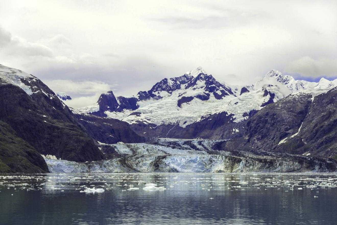Una cadena montañosa con un glaciar derritiéndose a sus pies.